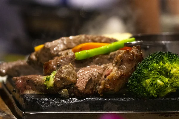 Close up beef on hot dish on fire with vegetables. Live cooking in the restaurant.