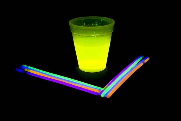 Yellow colored fluorescent glass with glow sticks lights — Stock Photo, Image