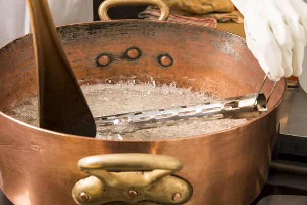 termometre ve büyük kaşık ile bakır tavada şeker şurubu kaynar