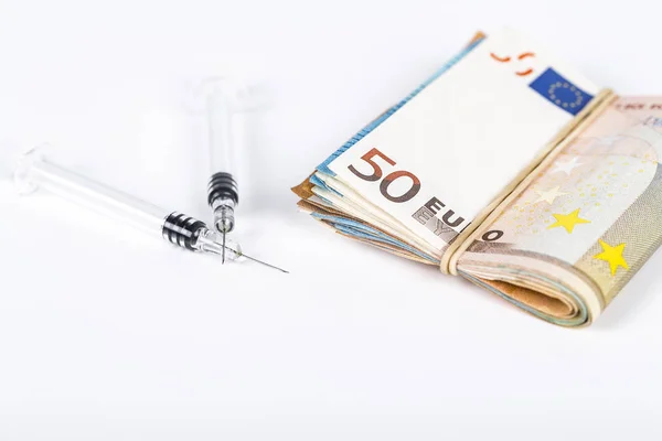 Jeringas médicas en fajo de varios billetes en euros — Foto de Stock