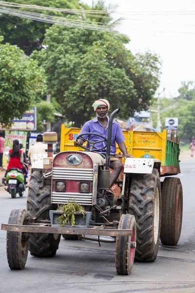 Dokumentarisches Redaktionsbild. Ein unbekannter Mann sitzt auf einem Traktor mit Anhänger auf der Straße. glücklicher Mann. — Stockfoto