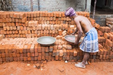 Belgesel yayın görüntü. Adam tuğla büyük bir tabak içinde alır.
