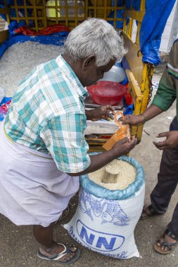 Belgesel yayın görüntü. Kimliği belirsiz bir Hintli onun açık Dükkanı Satıyoruz, Tamil Nadu bir küçük kırsal köy pazarda pirinç kurutulmuş.
