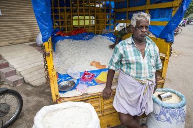 Belgesel yayın görüntü. Kimliği belirsiz bir Hintli onun açık Dükkanı Satıyoruz, Tamil Nadu bir küçük kırsal köy pazarda pirinç kurutulmuş.