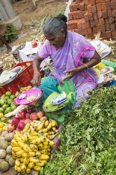 Belgesel yayın görüntü. Kimliği belirsiz bir Hint Tamil Nadu küçük kırsal köy pazarında meyve ve sebze onun dükkanında.