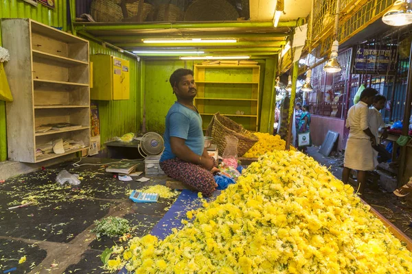 Imagen editorial documental. Mujer hombre no identificado vender creando cuerdas de flores en el mercado principal al aire libre en la India . — Foto de Stock