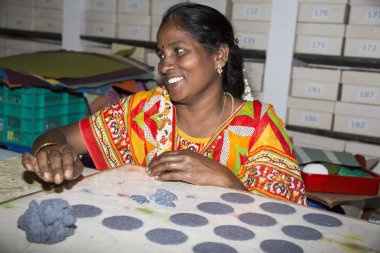 Belgesel yayın. Yaklaşık, Puduchery, Pondichery, Tamil Nadu, Hindistan - 2018 Mart. Kimliği belirsiz kadın kadın sanatçı el ile jewelleries kağıt olun. Küpe, kolye, çiçek. Kağıt geri dönüşüm ile.