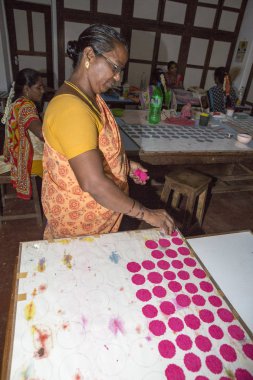 Belgesel yayın. Yaklaşık, Puduchery, Pondichery, Tamil Nadu, Hindistan - 2018 Mart. Kimliği belirsiz kadın kadın sanatçı el ile jewelleries kağıt olun. Küpe, kolye, çiçek. Kağıt geri dönüşüm ile.