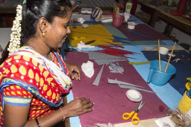 Belgesel yayın. Yaklaşık, Puduchery, Pondichery, Tamil Nadu, Hindistan - 2018 Mart. Kimliği belirsiz kadın kadın sanatçı el ile jewelleries kağıt olun. Küpe, kolye, çiçek. Kağıt geri dönüşüm ile.