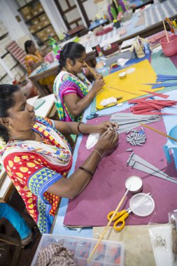 Belgesel yayın. Yaklaşık, Puduchery, Pondichery, Tamil Nadu, Hindistan - 2018 Mart. Kimliği belirsiz kadın kadın sanatçı el ile jewelleries kağıt olun. Küpe, kolye, çiçek. Kağıt geri dönüşüm ile.