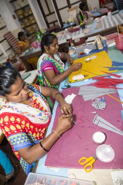 Belgesel yayın. Yaklaşık, Puduchery, Pondichery, Tamil Nadu, Hindistan - 2018 Mart. Kimliği belirsiz kadın kadın sanatçı el ile jewelleries kağıt olun. Küpe, kolye, çiçek. Kağıt geri dönüşüm ile.