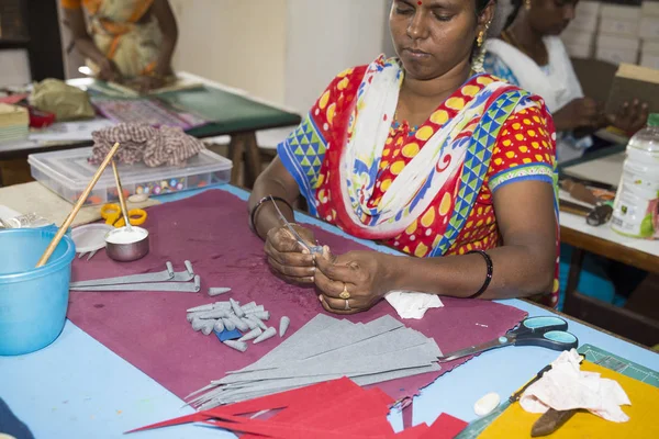 Belgesel yayın. Yaklaşık, Puduchery, Pondichery, Tamil Nadu, Hindistan - 2018 Mart. Kimliği belirsiz kadın kadın sanatçı el ile jewelleries kağıt olun. Küpe, kolye, çiçek. Kağıt geri dönüşüm ile.