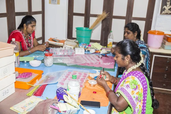Belgesel yayın. Yaklaşık, Puduchery, Pondichery, Tamil Nadu, Hindistan - 2018 Mart. Kimliği belirsiz kadın kadın sanatçı el ile jewelleries kağıt olun. Küpe, kolye, çiçek. Kağıt geri dönüşüm ile.