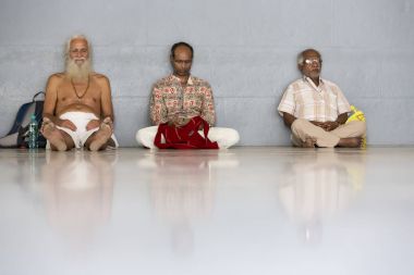 Belgesel yayın. Ashram'daki Sri Ramana Maharshi, Tiruvannamalai, Tamil Nadu, Hindistan - Mart yaklaşık, 2018. Kimliği belirsiz bir kadın ve maneviyat ashram meditasyon yapmak için katta oturan adam.