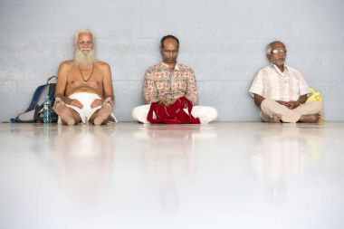 Belgesel yayın. Ashram'daki Sri Ramana Maharshi, Tiruvannamalai, Tamil Nadu, Hindistan - Mart yaklaşık, 2018. Kimliği belirsiz bir kadın ve maneviyat ashram meditasyon yapmak için katta oturan adam.