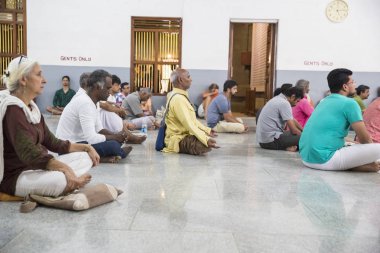 Belgesel yayın. Ashram'daki Sri Ramana Maharshi, Tiruvannamalai, Tamil Nadu, Hindistan - Mart yaklaşık, 2018. Kimliği belirsiz bir kadın ve maneviyat ashram meditasyon yapmak için katta oturan adam.