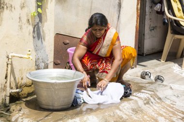 Documentary editorial. PUDUCHERY, PONDICHERY, TAMIL NADU, INDIA - March circa, 2018. Unidentified indian woman wash laundry clothes outdoors. clipart