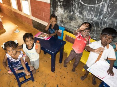 Sevimli zavallı küçük çocuk, erkek kızlar, masada sandalyede oturan, kitap okumaya çalışıyor
