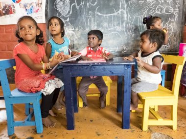 Sevimli zavallı küçük çocuk, erkek kızlar, masada sandalyede oturan, kitap okumaya çalışıyor