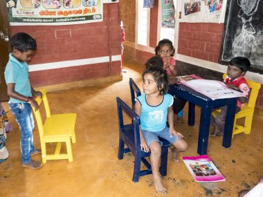 Sevimli zavallı küçük çocuk, erkek kızlar, masada sandalyede oturan, kitap okumaya çalışıyor