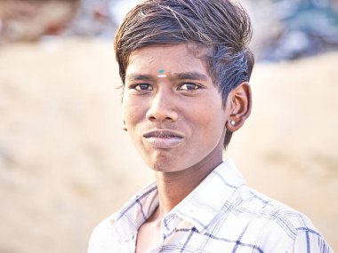 PUDUCHERRY, İNDİA - Aralık 2018. Köyün sokaklarında gülümseyen ve gururlu yüzlü Hintli bir gencin portresi. Canlı renklerle ön görünüm