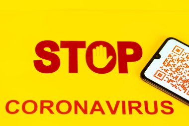 Coronavirus Covid-19 enfeksiyonu için çalışan işçilerin sağlık virüsü enfeksiyonunu bilmeleri için kullanılan akıllı telefon ekranında kırmızı QR kodu ile Dur İşareti. Sarı arka plan. Dünyada salgın virüse karşı yeni bir yol