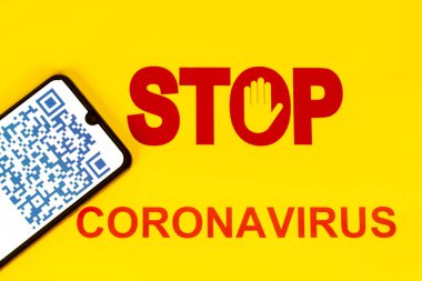 Coronavirus Covid-19 enfeksiyonu için akıllı telefon ekranında mavi renkli QR kodu olan Dur İşareti işçilerin sağlık virüsü enfeksiyonunu öğrenmesi için kullanılıyor. Sarı arka plan. Dünyada salgın virüse karşı yeni bir yol