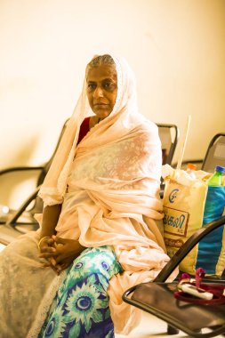 Puducherry, Hindistan - Mart 2020. Hastanenin içinde koruyucu maske takmayan bir kadın koronavirüs ve diğer sağlık hastalıkları için sağlık kontrolü bekliyor. Üzgün ve yorgun duygular