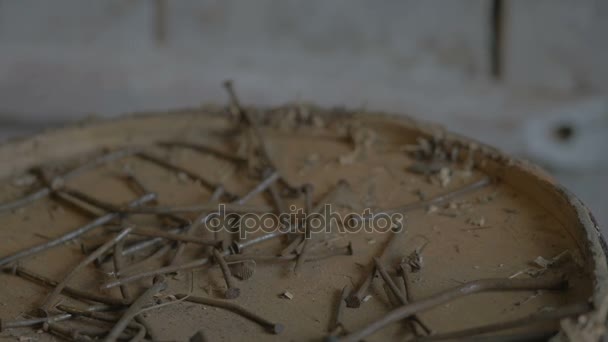 Pracující člověk vylévá rezavé hřebíky na stole v dílně na zdi dřevěný venkovský dům farma. — Stock video