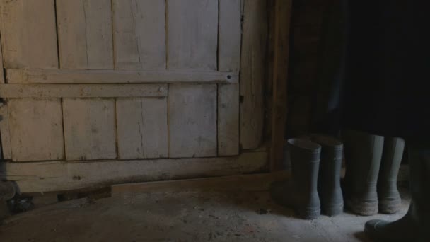 Um homem de botas de borracha entra com uma cesta de colheita e entra no celeiro, 4K — Vídeo de Stock