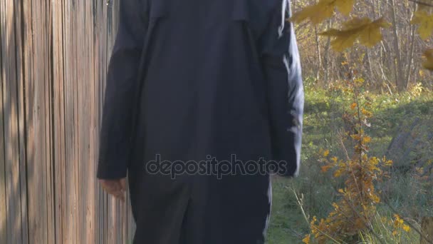 Un hombre, caminando a lo largo de la carretera en el pueblo en el día de otoño. Enfoque superficial . — Vídeos de Stock