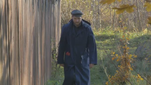 Ein Mann, der an einem Herbsttag die Straße im Dorf entlanggeht. Oberflächlicher Fokus. — Stockvideo