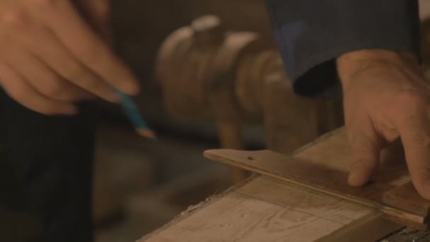 Snickarmästare gör tråckla på tavlan med en penna, dragningar, hantverkare arbetsredskap i verkstaden. — Stockvideo