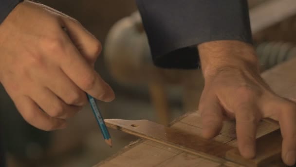 Maestro carpintero hace la cocción en el tablero con un lápiz, dibuja, herramienta de trabajo del artesano en el taller . — Vídeos de Stock