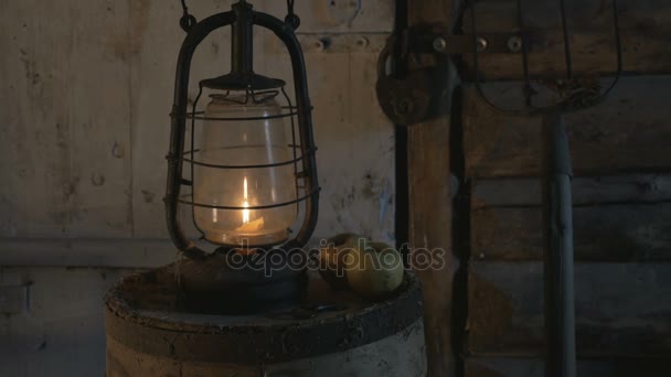 Lámpara antigua con vela en una mesa de madera con manzanas en la noche, el agricultor trajo una lámpara, una linterna, iluminó la habitación 4K — Vídeo de stock