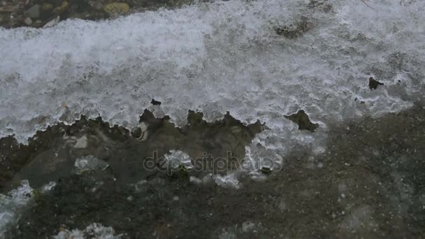 In inverno, una bella acqua cristallina che lambisce la riva nel ghiaccio. acqua attraverso lo scioglimento del ghiaccio in inverno . — Video Stock