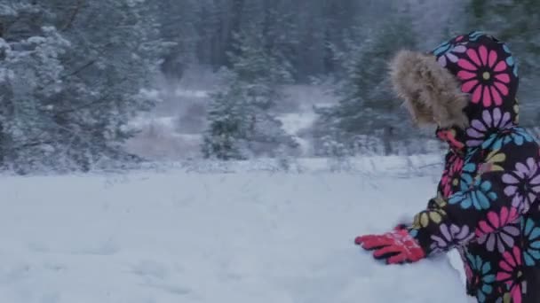 Steadicam. Una niña esculpe un muñeco de nieve en la nieve en el invierno . — Vídeos de Stock