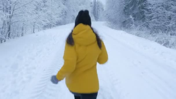 Девушка бежит по дороге в зимнем лесу. Ноги крупным планом снизу — стоковое видео