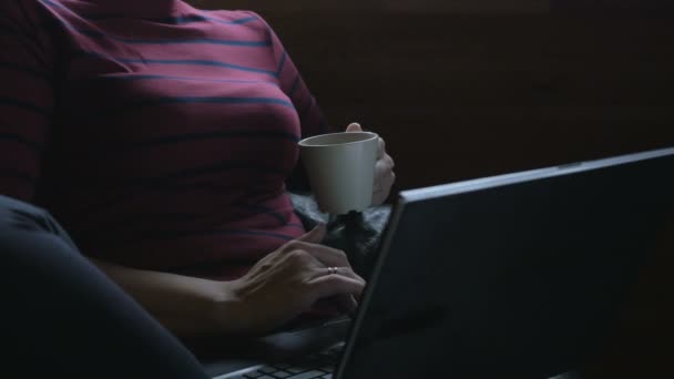 Dizüstü bilgisayar ile sandalyede oturan ve çay içme kız. Evden çalışma. — Stok video