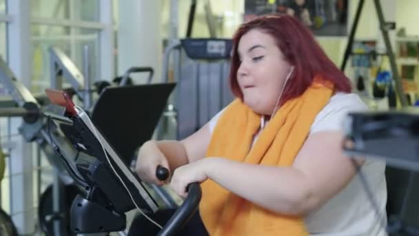 Mujer completa practicando en bicicleta en el gimnasio — Vídeo de stock