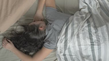 Taze ve mutlu kadın yatakta gözleri ve gülümsüyor, açılış sabah uyanıyor sonra tekrar uykuya dalar. Üstten Görünüm