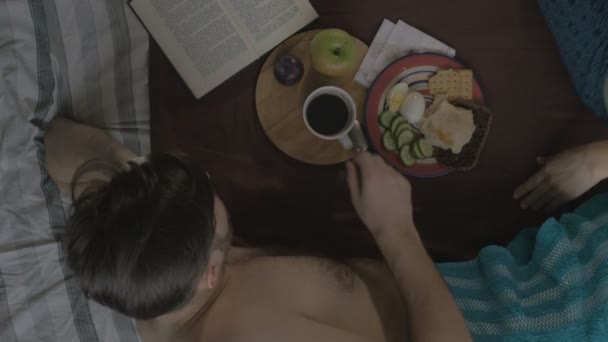 Νεαρός άνδρας τρώει νόστιμο πρωινό το πρωί με ένα κορίτσι. Η θέα από την κορυφή — Αρχείο Βίντεο