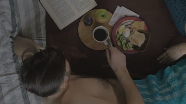 Joven comiendo sabroso desayuno por la mañana con una chica. La vista desde arriba — Vídeos de Stock