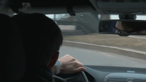 Молодой человек медленно водит машину в городе . — стоковое видео