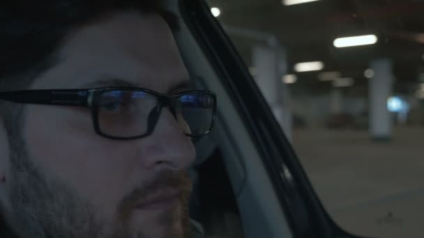 地下駐車場で車を運転する男。クローズ アップ。背景のボケ味 — ストック動画