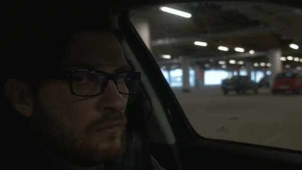 Un homme conduisant la voiture au parking souterrain. Ferme là. Bokeh fond — Video