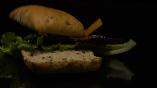 La hamburguesa cae en acción lenta sobre la mesa — Vídeo de stock