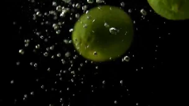 Slo-motion limón entero y cal cayendo sobre el agua — Vídeo de stock