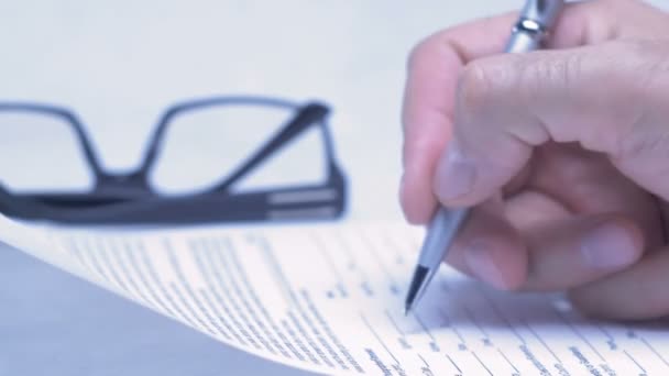 Male hand is writing in business document lying on the table. Close-up. — Stock Video