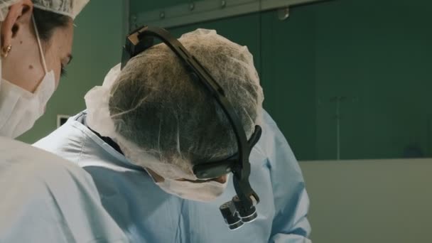 Лікар в захисному одязі, що виконує операцію з використанням стерилізованого обладнання — стокове відео